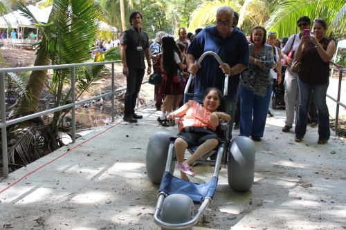 María López, inicia el recorrido de una vereda de la Reserva Natural Punta Tina, en Maunabo,  en una de las sillas especiales acompañada de su abuelo.