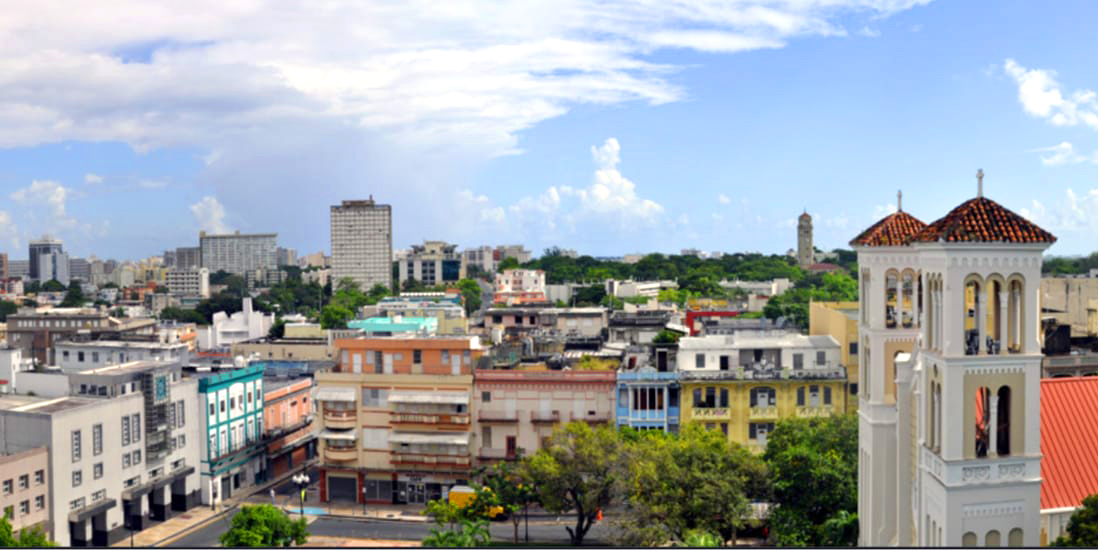 Calle comercial de Río Piedras con edificios de fachadas coloridas y árboles